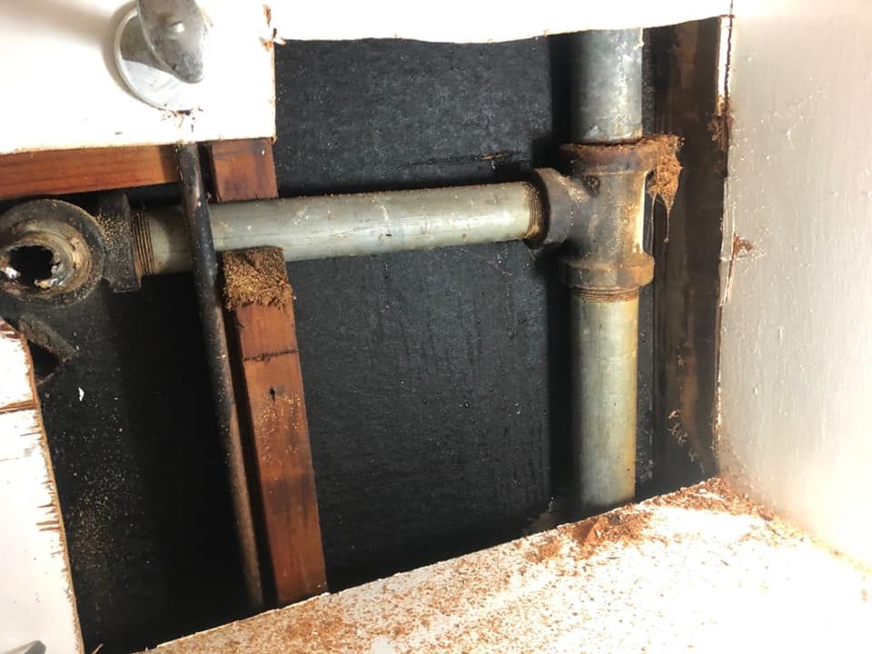 The galvanized pipes inside the wall before the repair